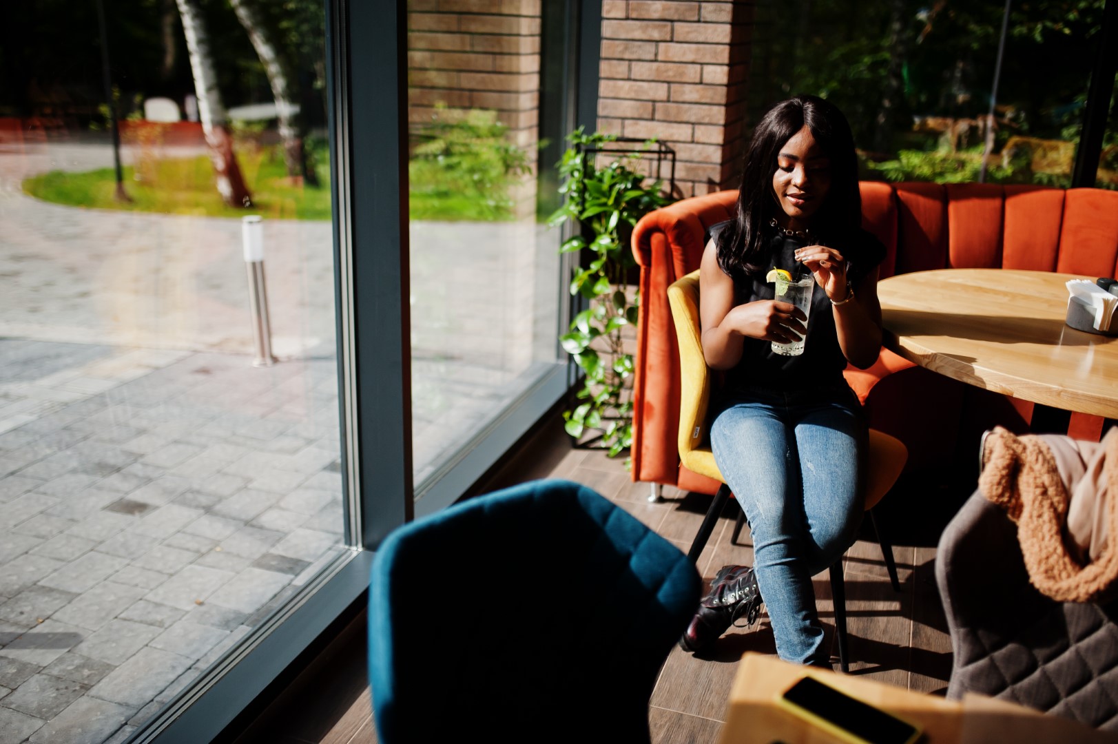 Fashionable african american woman at restaurant drink lemonade.